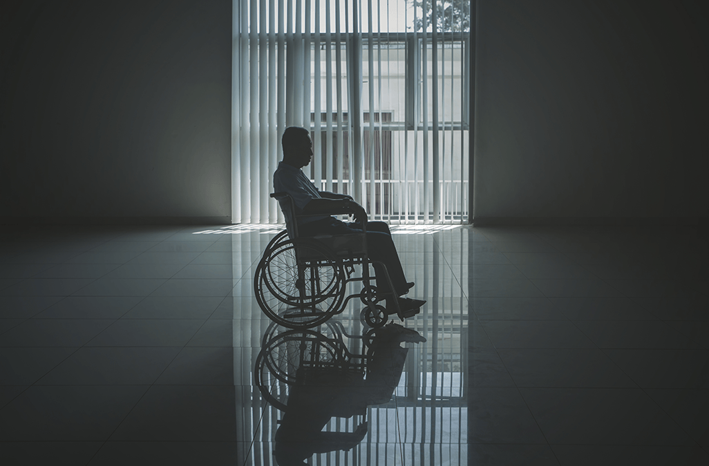 Photo of a man in wheelchair left alone in empty room