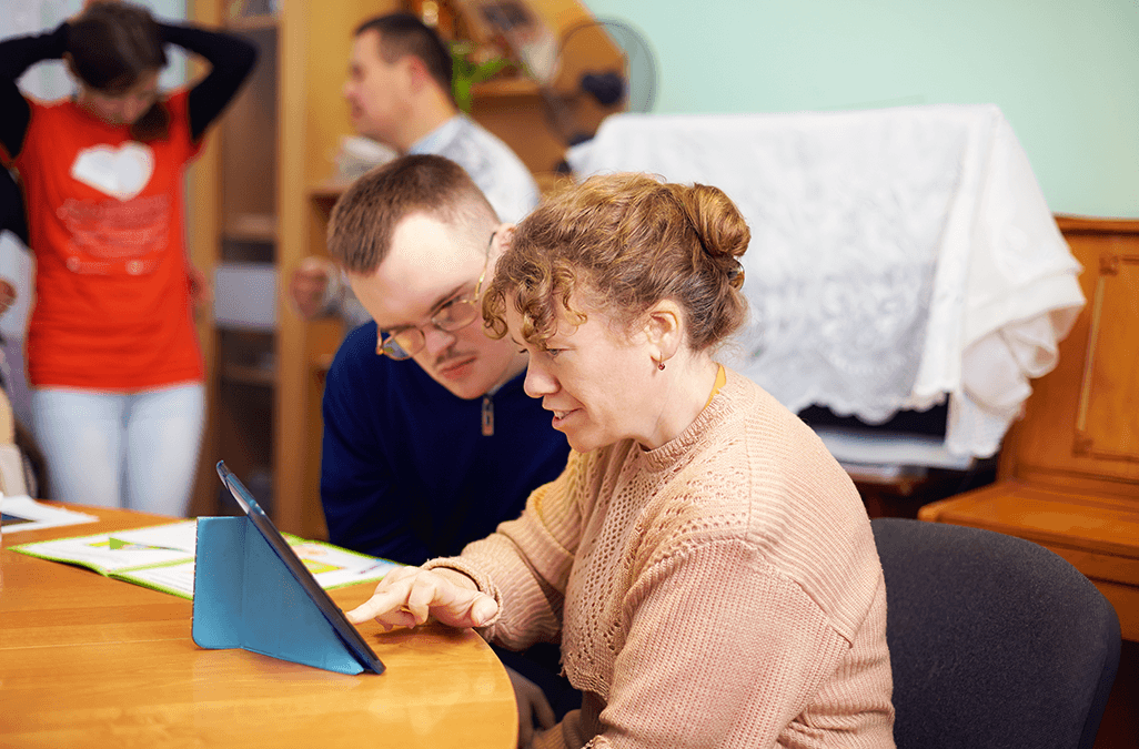 Photo of people with disability watching something on a tablet