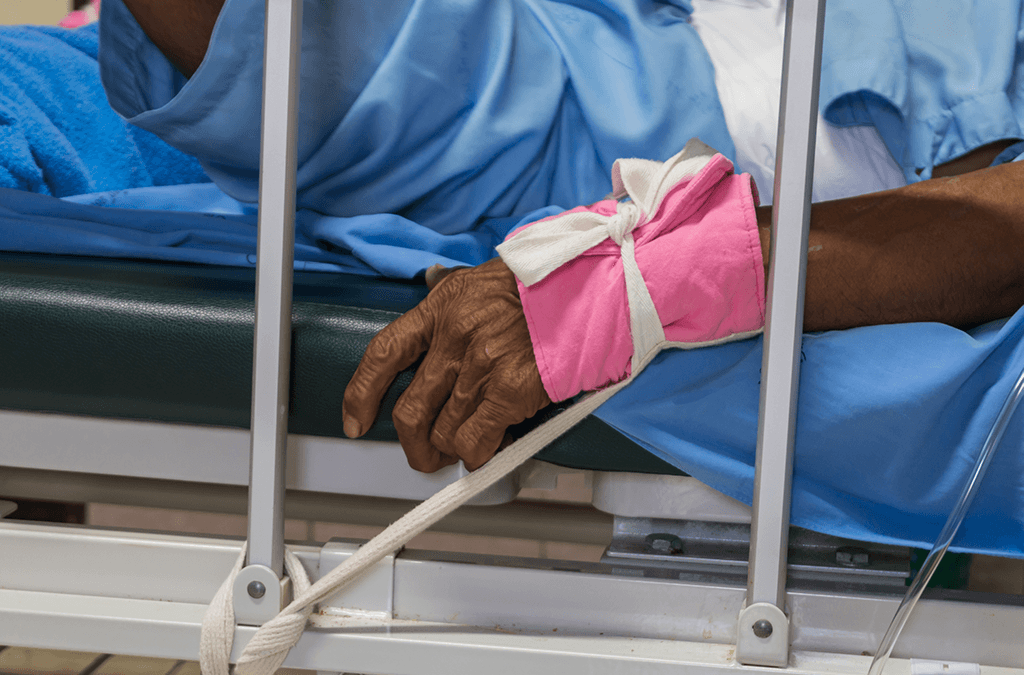 Photo of person in hospital with physical restraints