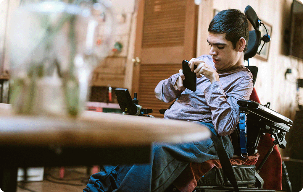 Male electric wheelchair user at dining table using his mobile phone
