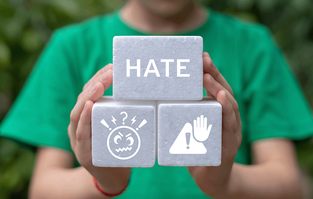 person holding 3 blocks, one says hate, another has an angry person icon and another has a warning icon